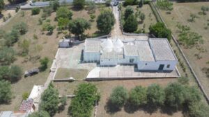 De te koop staande boerderij in Puglia van bovenaf te zien met de kegels van de trulli